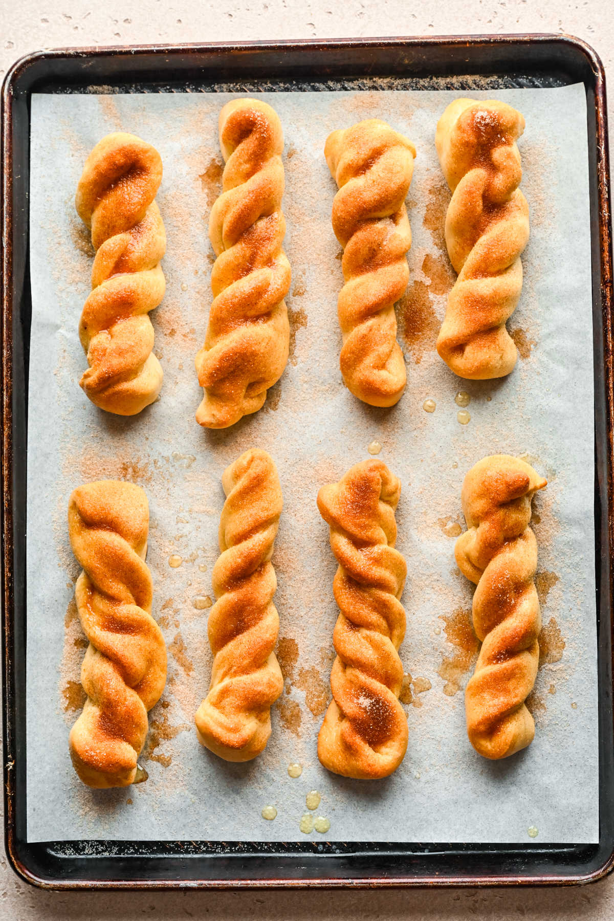 Cinnamon breadsticks on a parchment lined baking sheet.