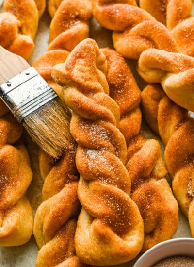 Close up photo of a cinnamon breadstick on top of a stack of cinnamon breadsticks.