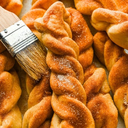 Close up photo of a cinnamon breadstick on top of a stack of cinnamon breadsticks.