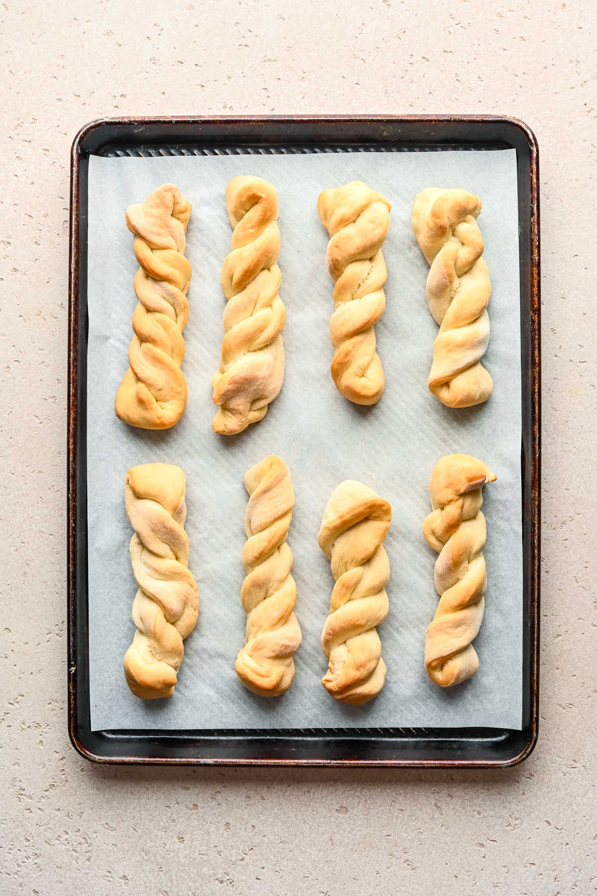 Baked cinnamon breadsticks on a parchment lined baking sheet.
