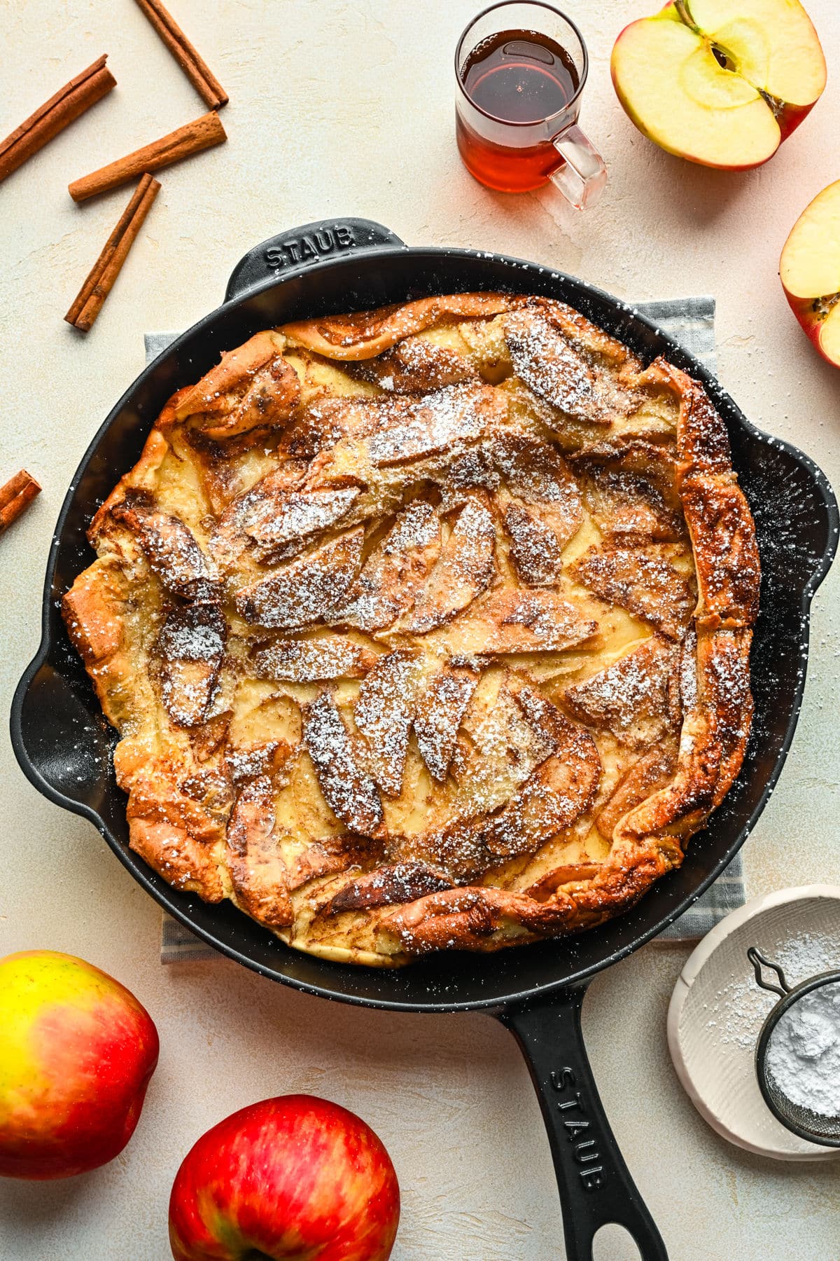 German apple pancake dusted with powdered sugar in a cast iron skillet.