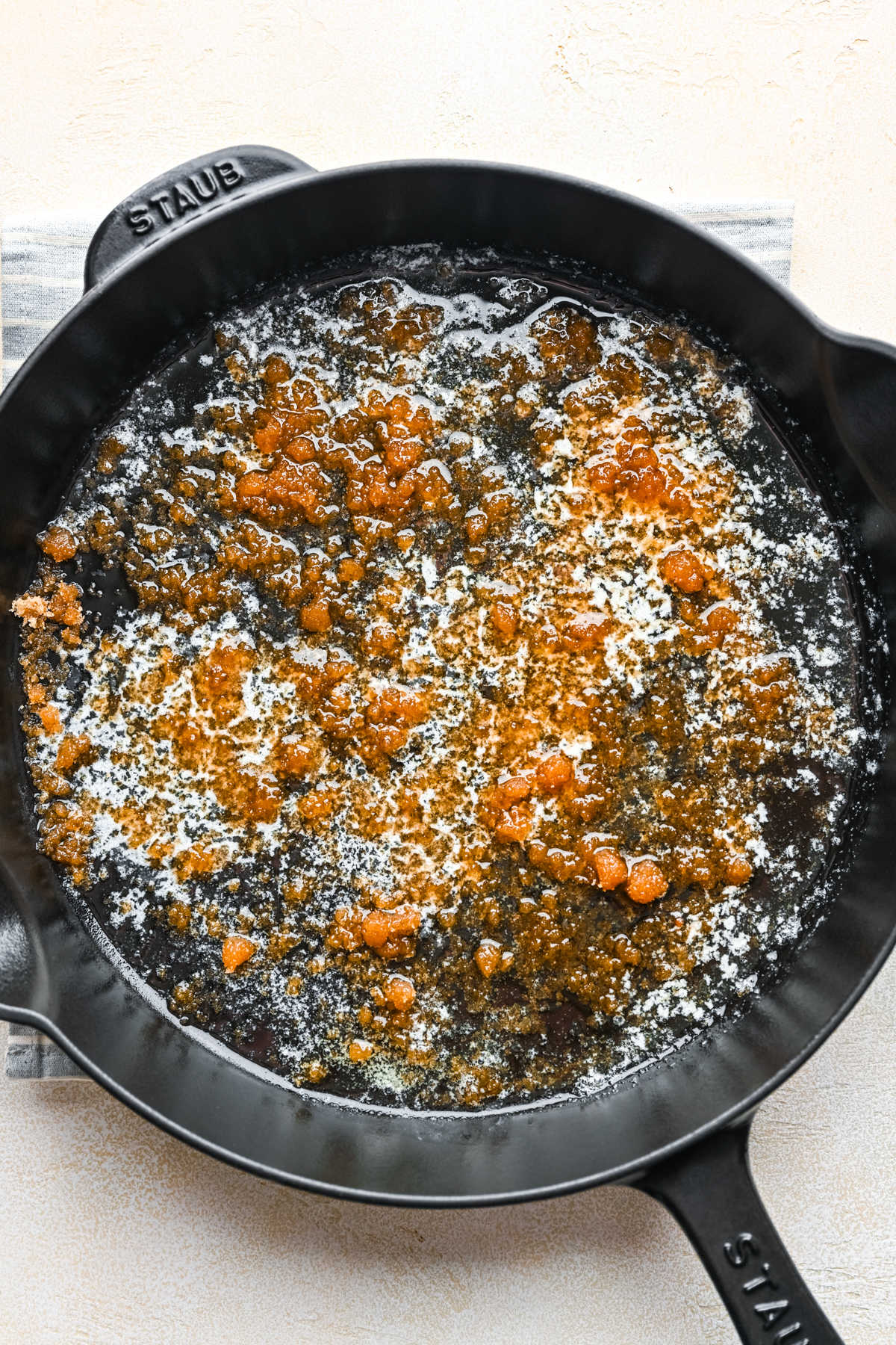 Brown sugar sprinkled over melted butter in a cast iron skillet.