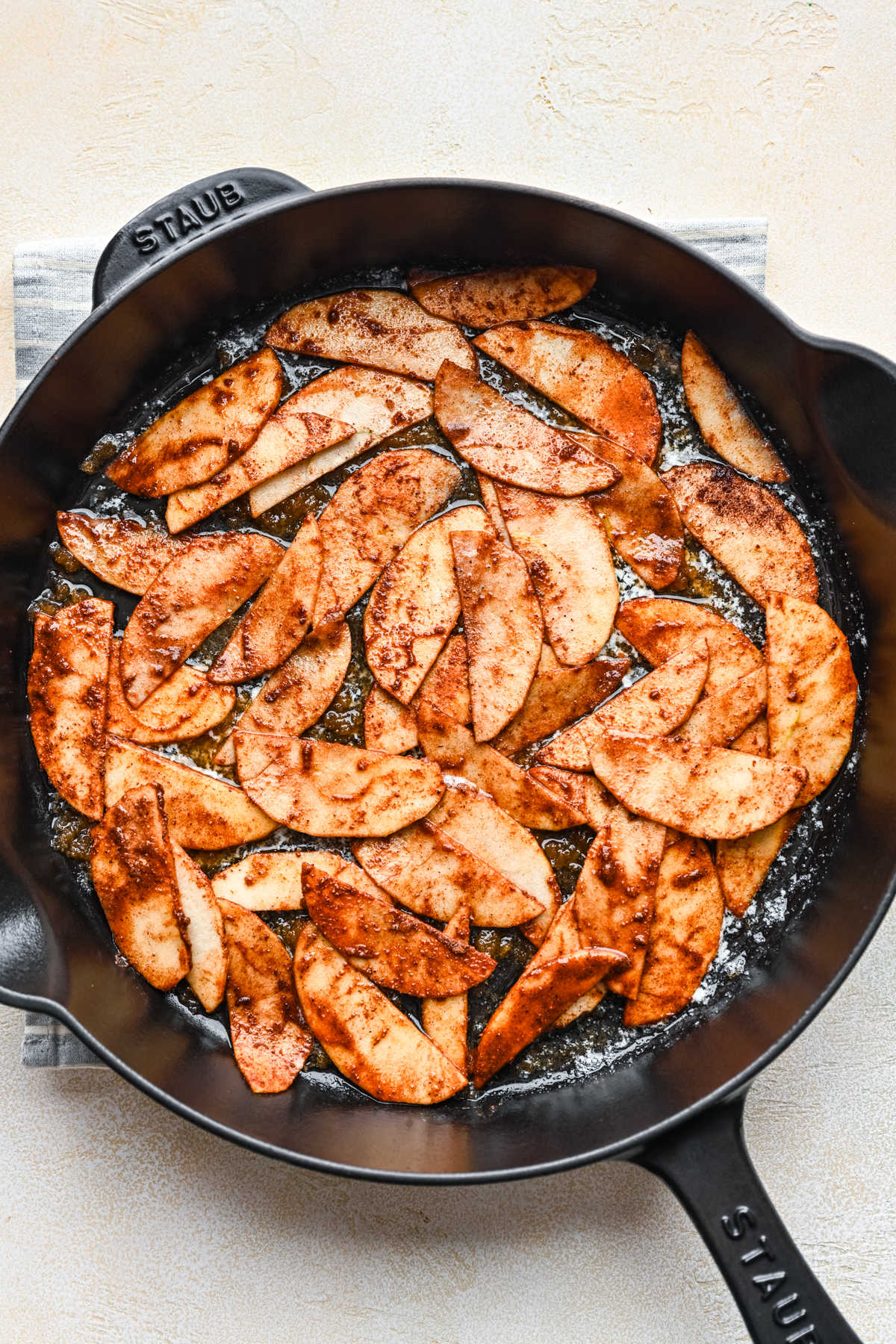 Cinnamon sugar coated apple slices in melted butter in a cast iron skillet.