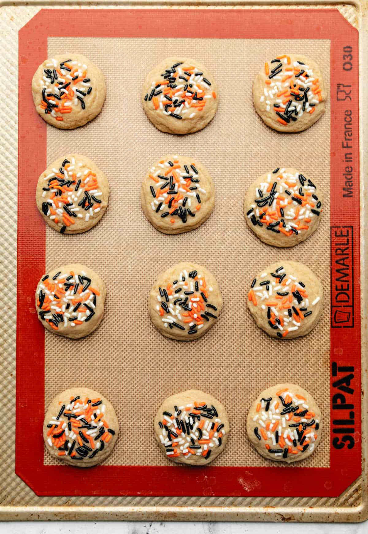 Baked Halloween sprinkle cookies on a silicone baking mat.