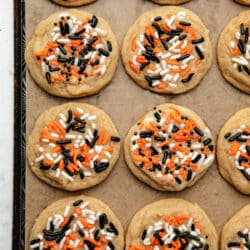 Rows of Halloween sprinkle cookies on a piece of brown parchment paper.