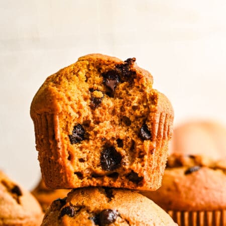 Half of a pumpkin chocolate chip muffin on top of another pumpkin muffin.