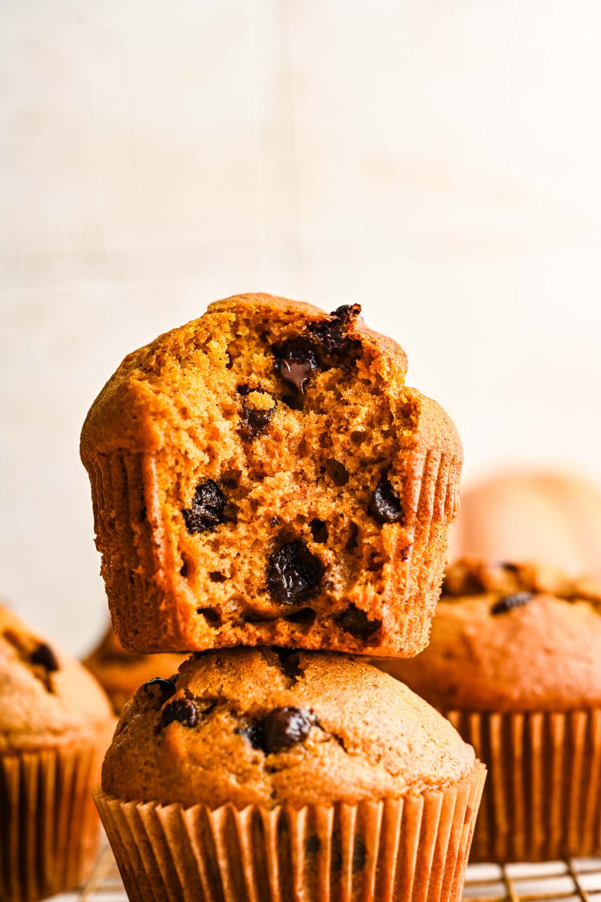 Pumpkin Chocolate Chip Muffin Recipe Half of a pumpkin chocolate chip muffin on top of another pumpkin muffin.