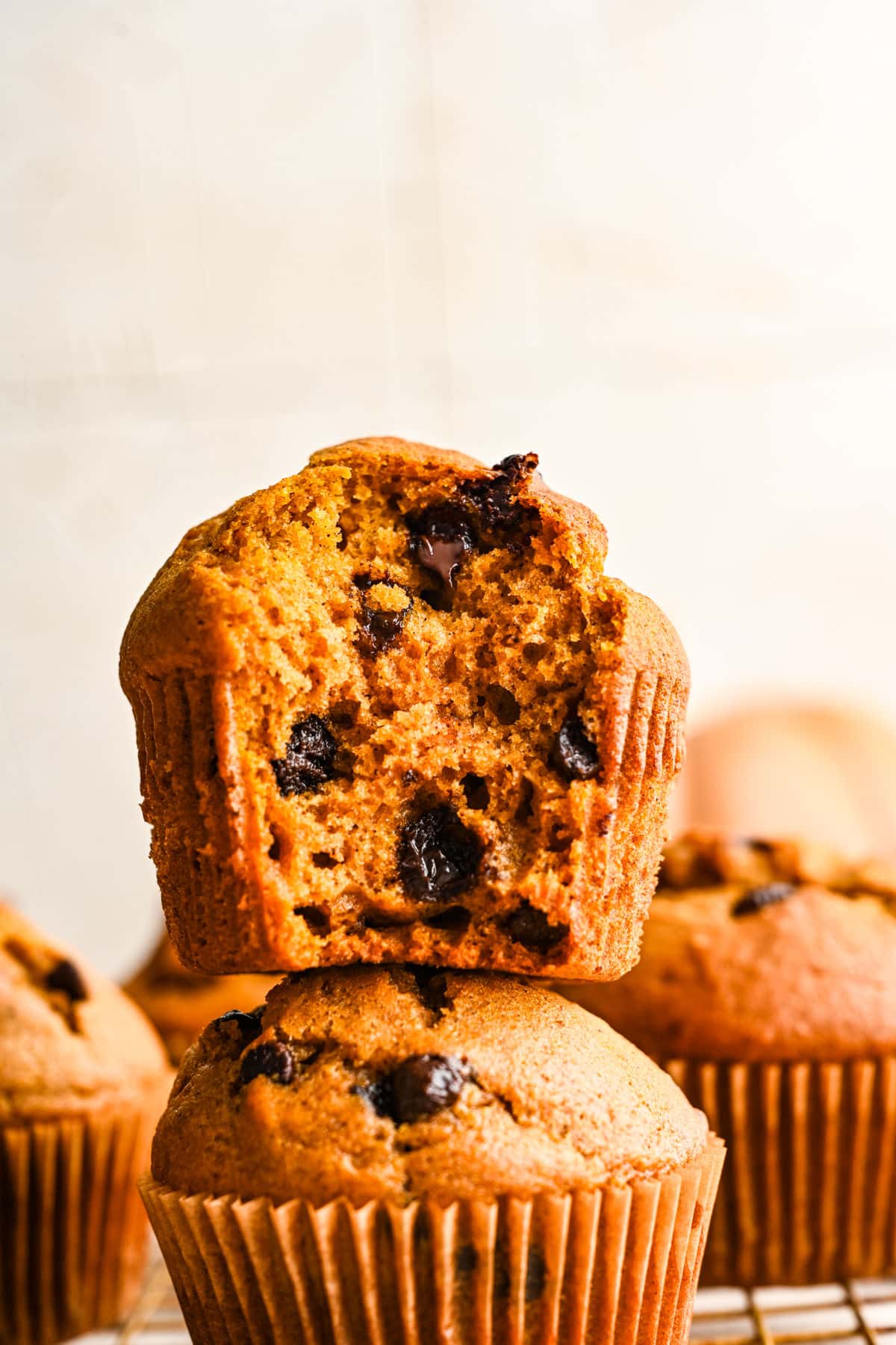 Half of a pumpkin chocolate chip muffin on top of another pumpkin muffin.