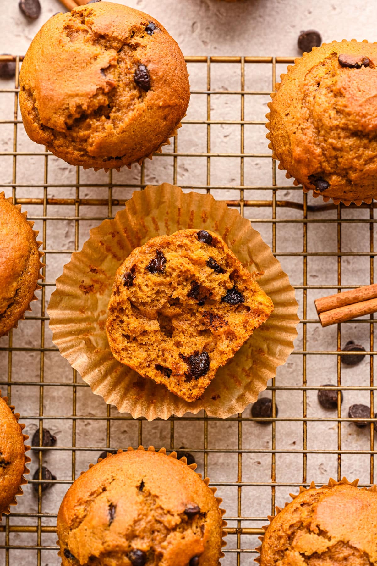 Half of a pumpkin chocolate chip muffin in a muffin liner on a wire cooling rack. 