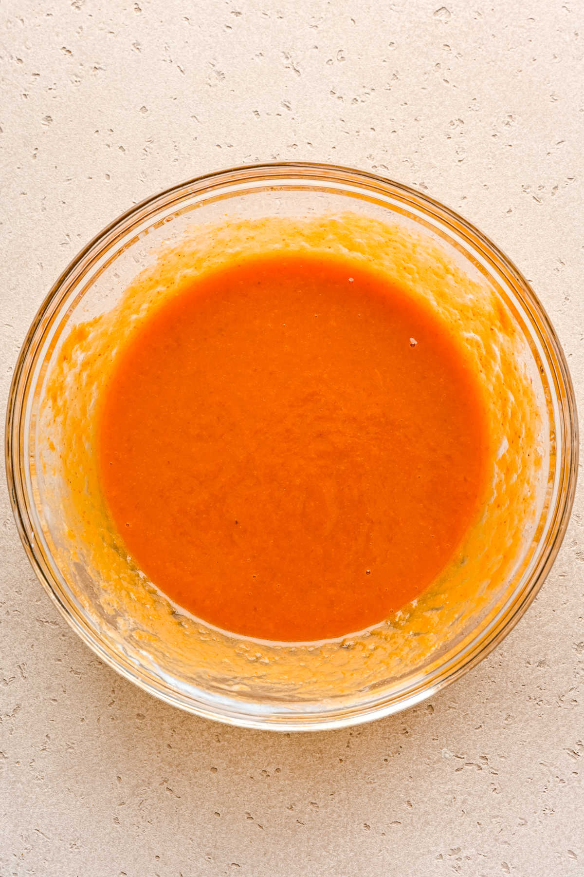 Wet ingredients for pumpkin chocolate chip muffins whisked together in a glass mixing bowl. 