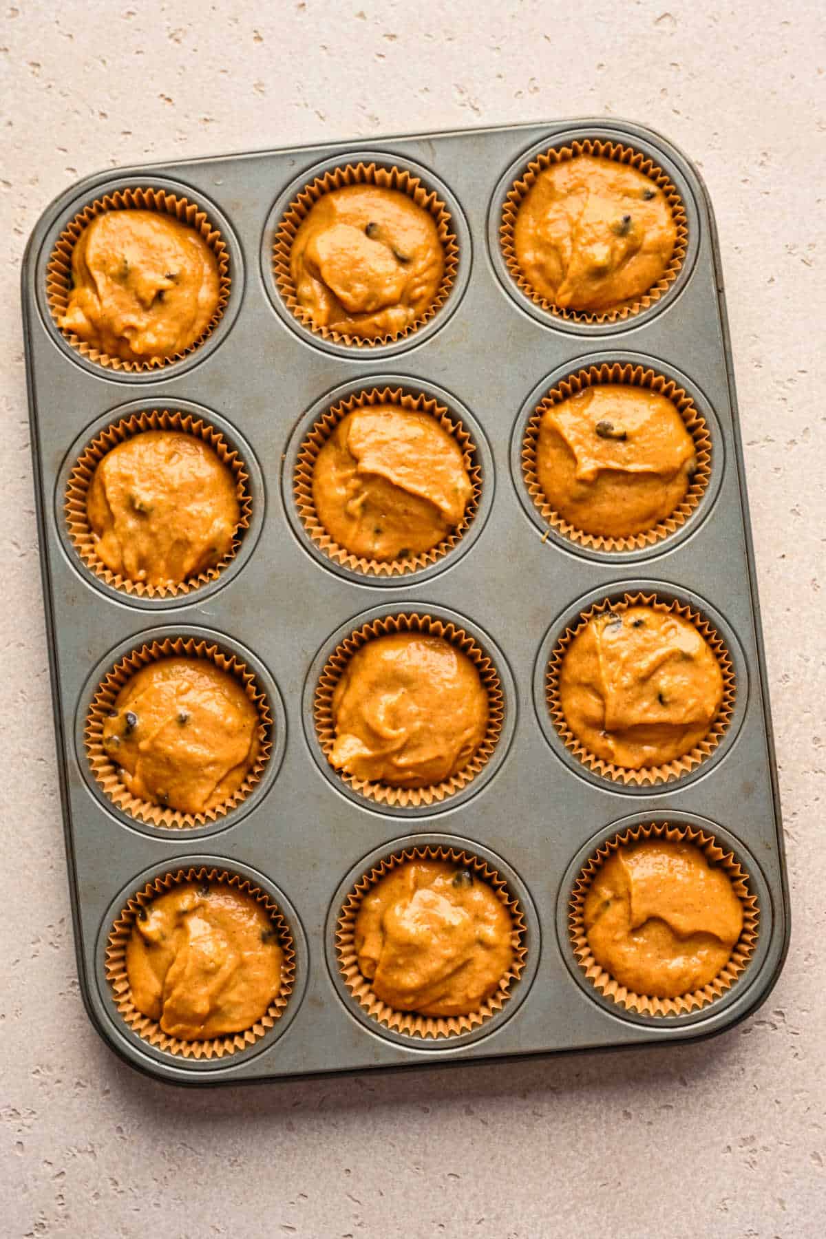 Pumpkin chocolate chip muffin batter in a muffin tin.