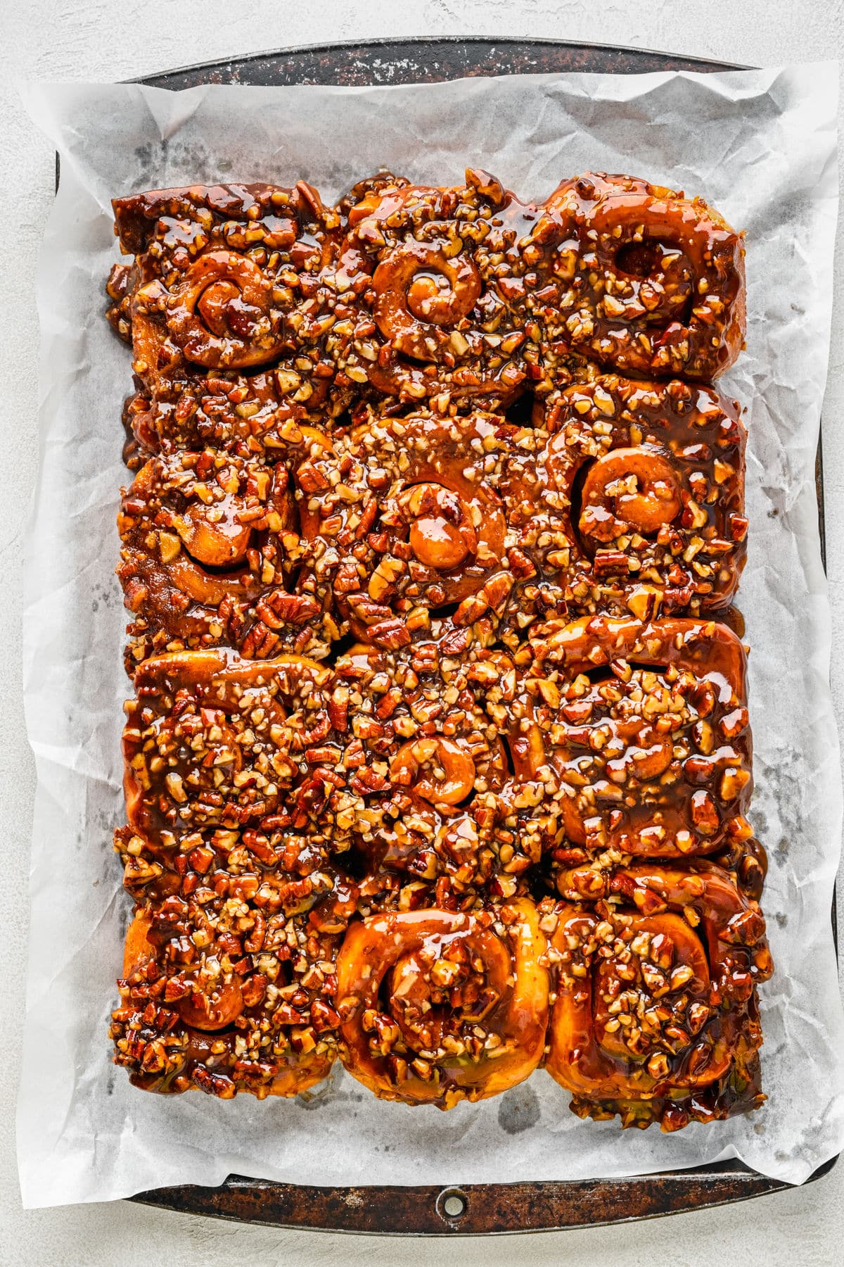 Inverted sticky buns on a parchment lined baking sheet. 