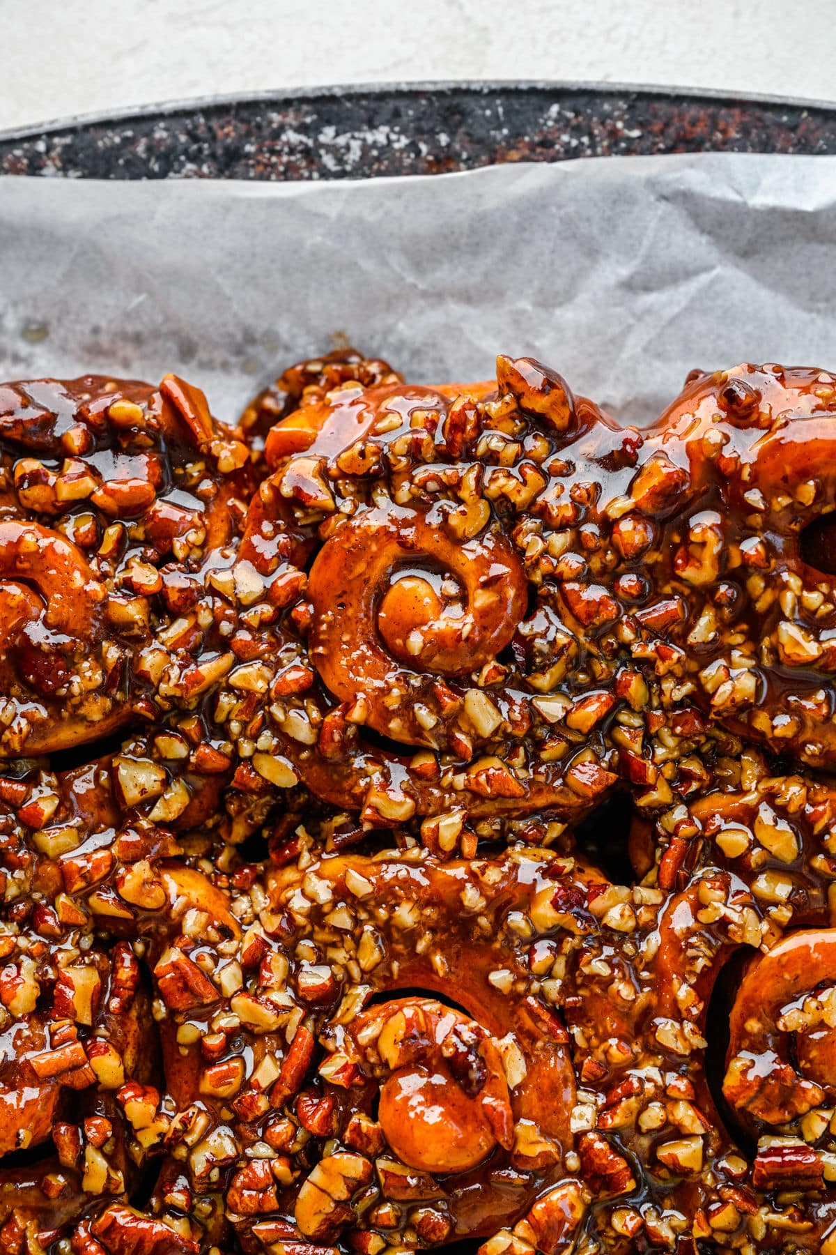 Close up photo of homemade sticky buns on a parchment lined baking tray.