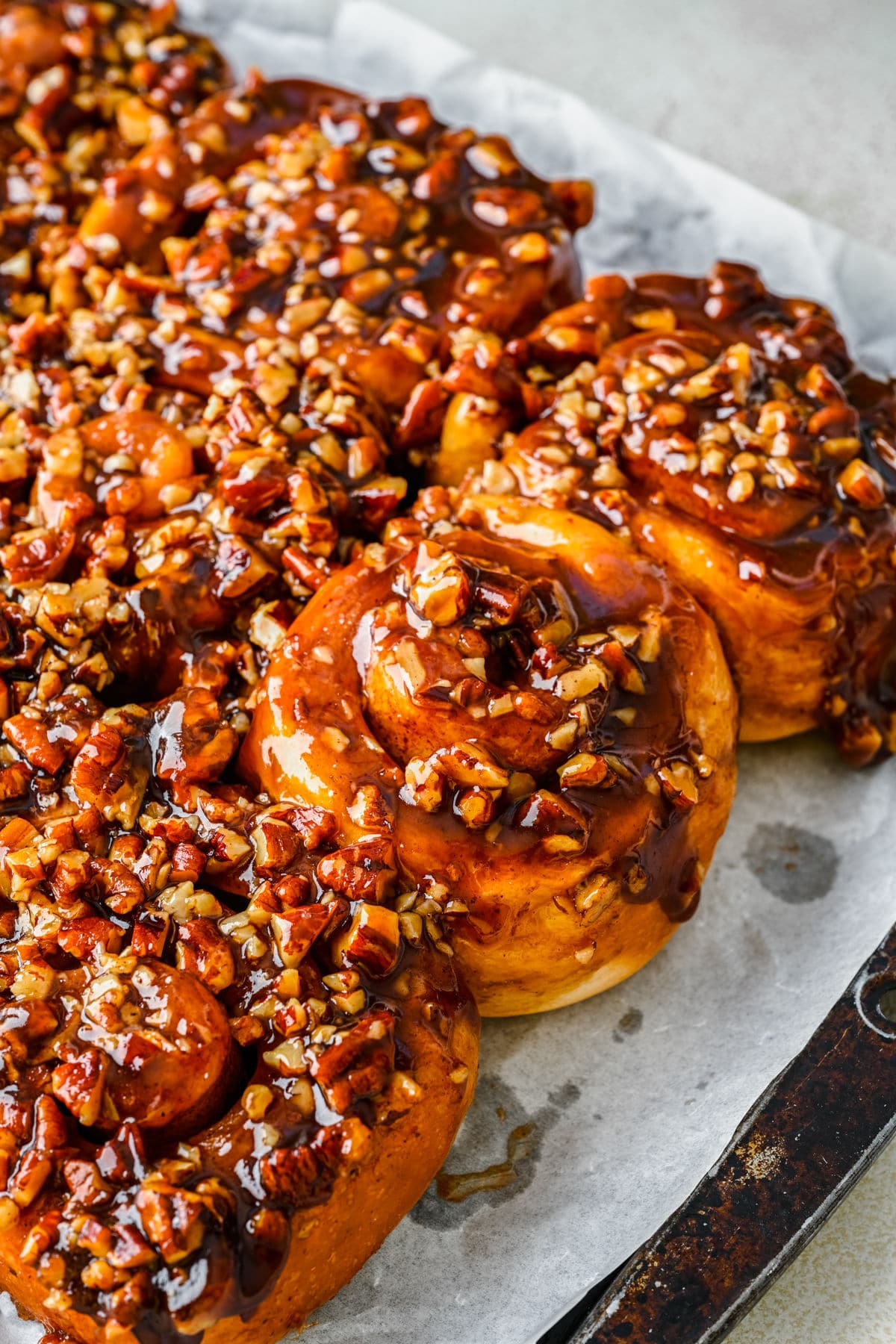 Homemade sticky buns on a parchment lined baking sheet.