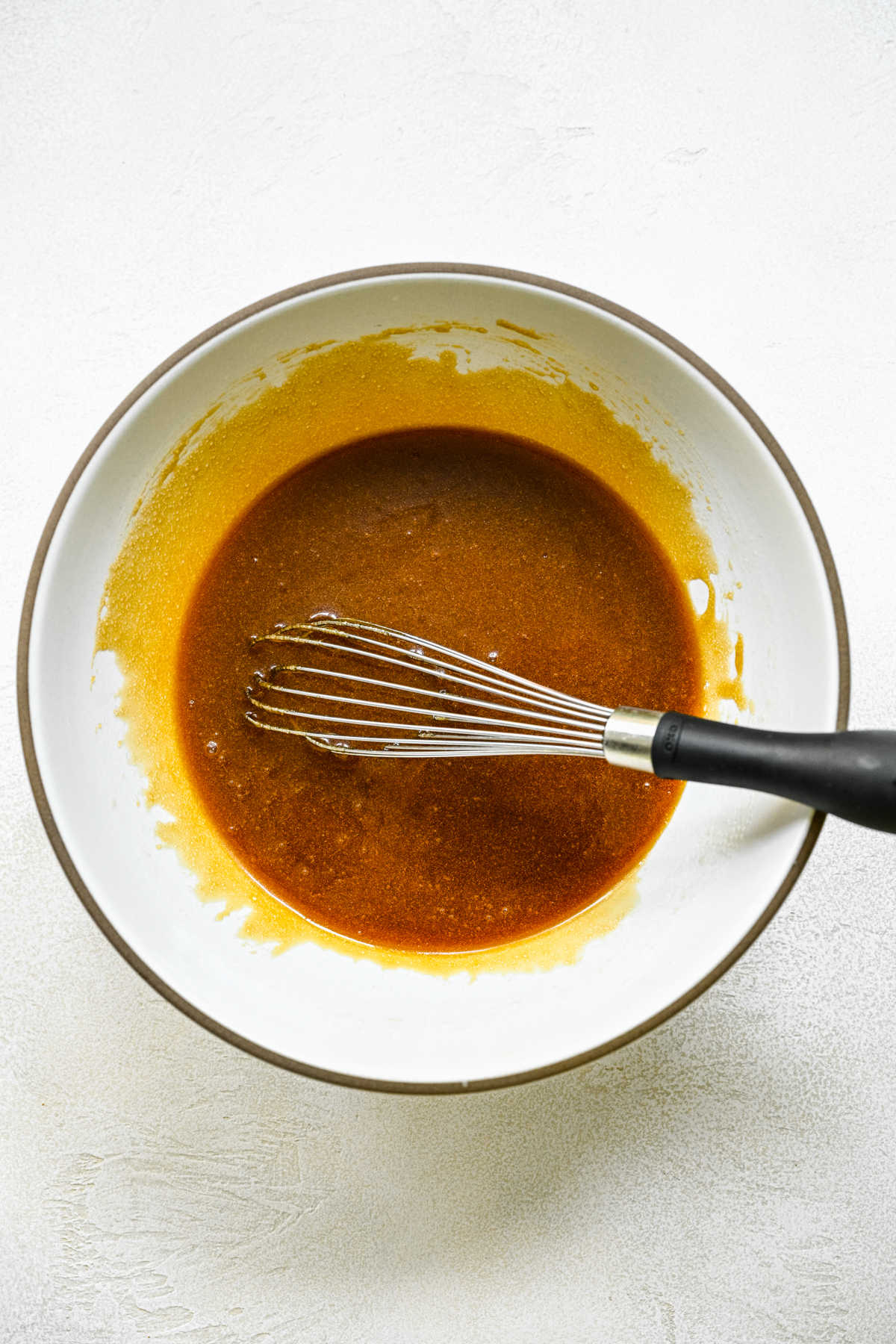 Sticky bun topping in a white mixing bowl with a whisk in it. 