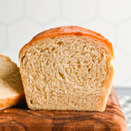 A loaf of homemade white bread with the slices cut off next to it.