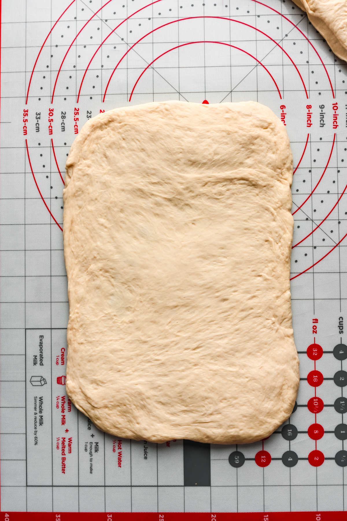 White bread dough rolled into a rectangle on a baking mat.