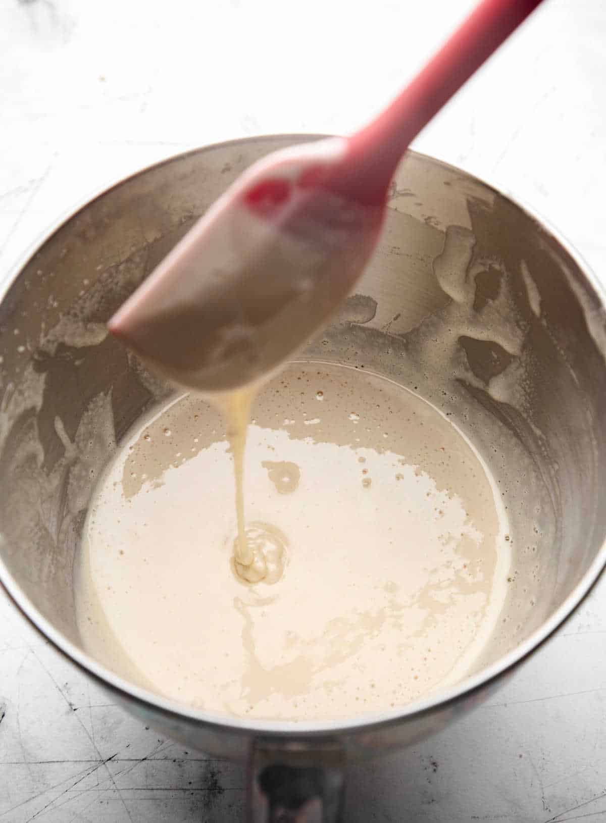 Egg mixture falling in a ribbon from a red spatula.