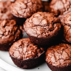 Brownie bites stacked on top of each other on a white plate.