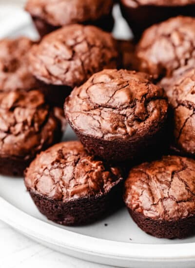 Brownie bites stacked on top of each other on a white plate.