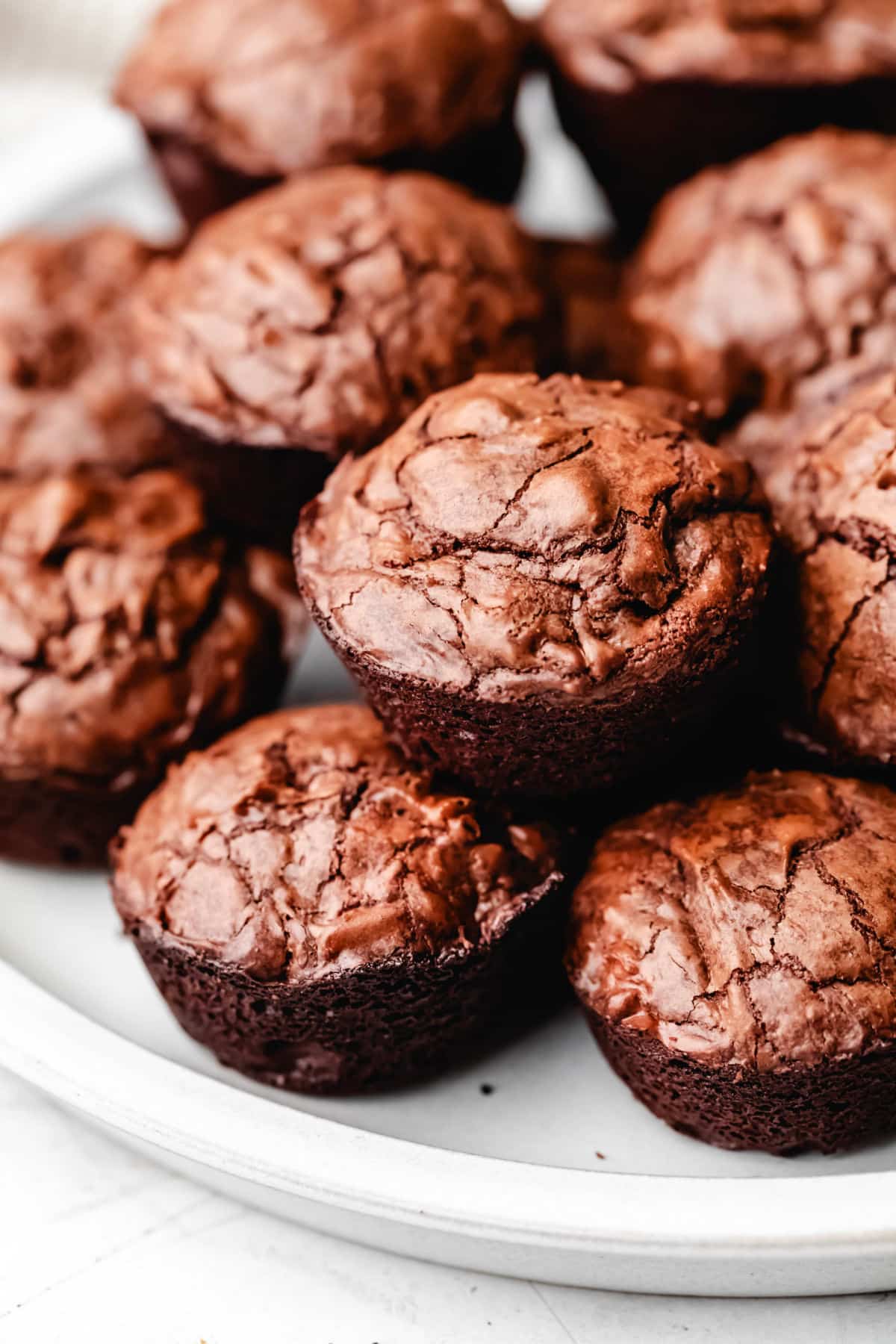 Brownie bites stacked on top of each other on a white plate.