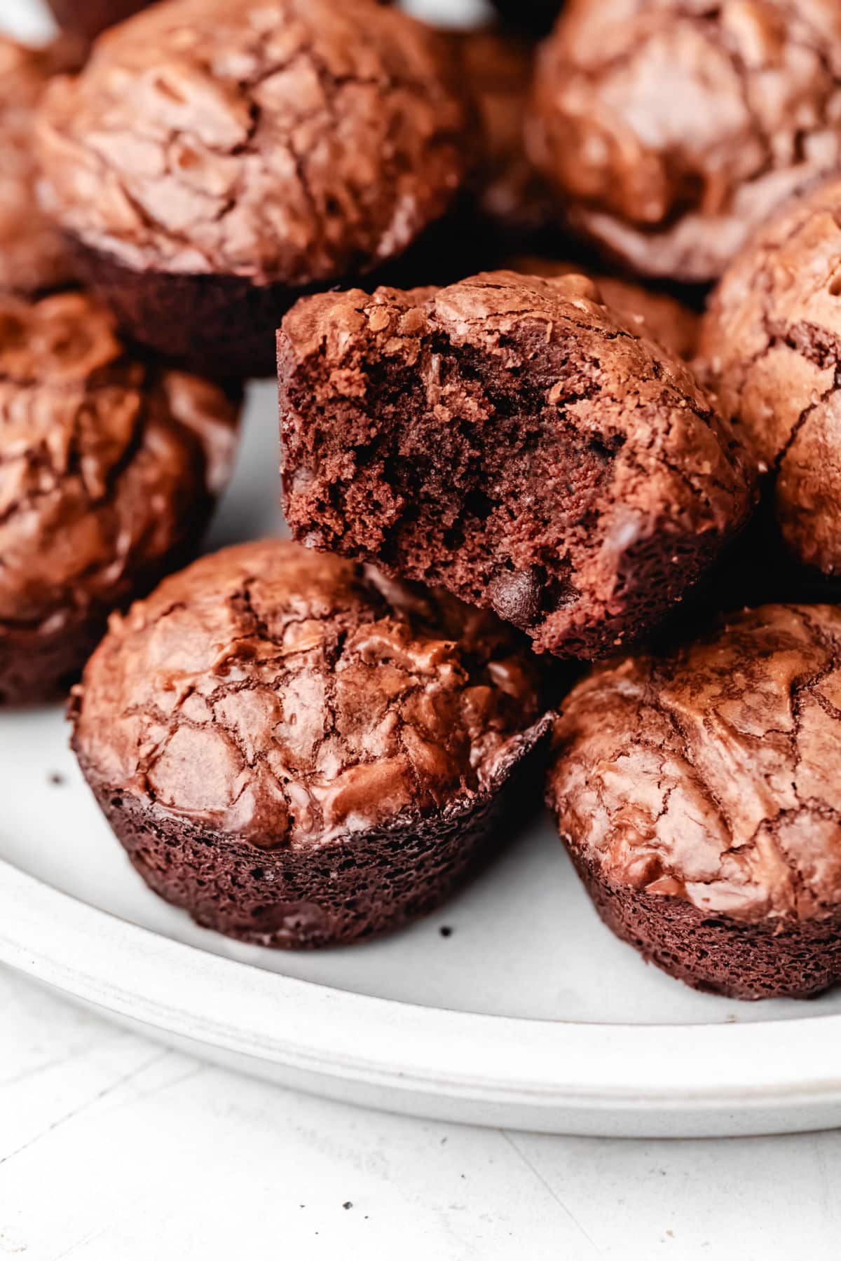 A brownie bite with a bite missing on top of a stack of brownie bites. 