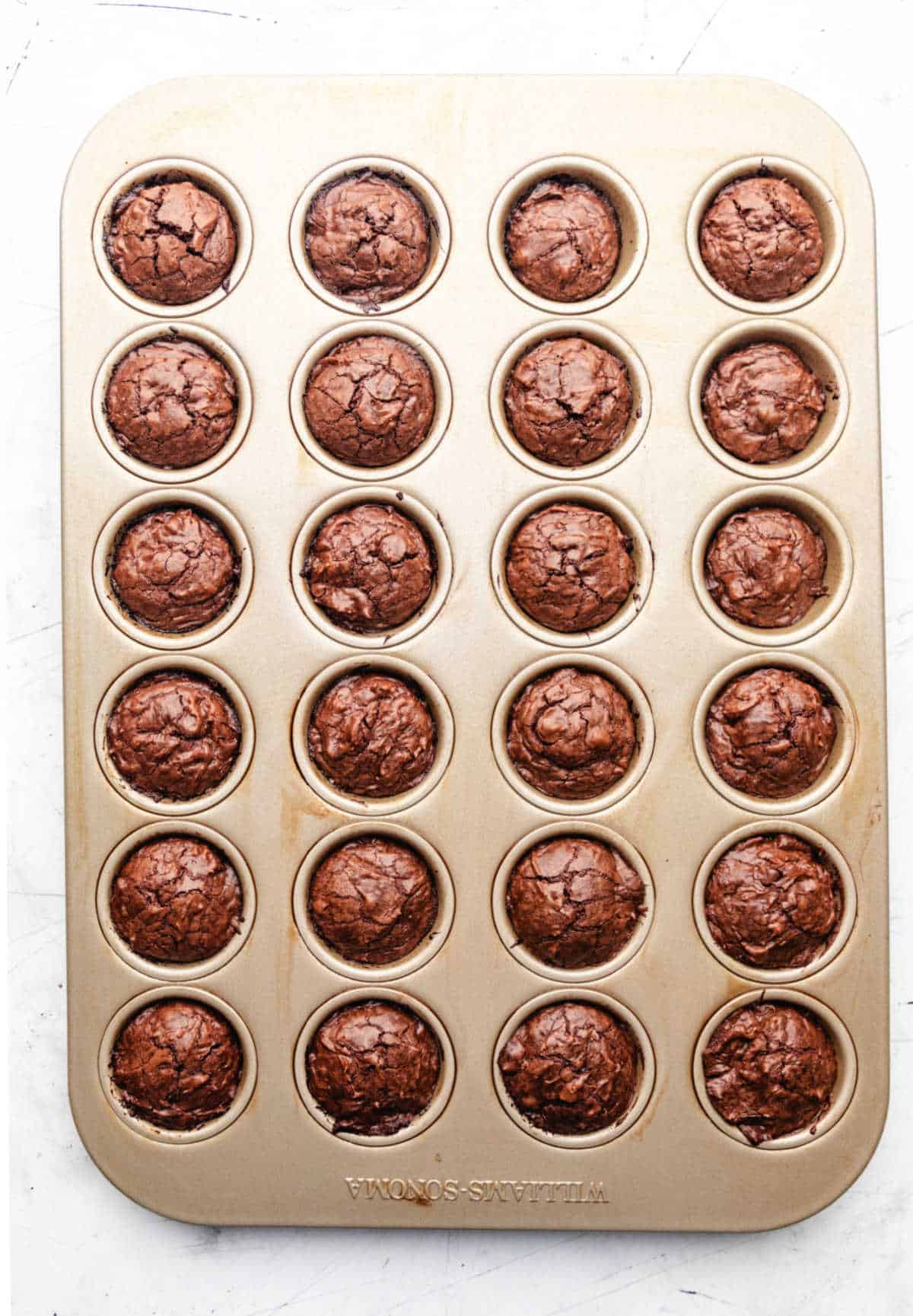 Baked mini brownie bites  in a gold mini muffin tin. 