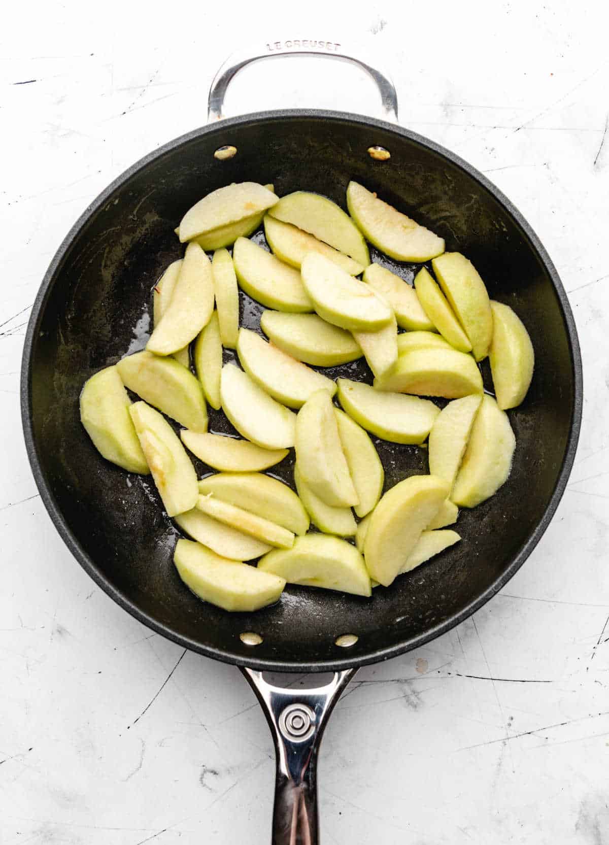 Apple slices sauteeing in butter in a cast iron skillet. 