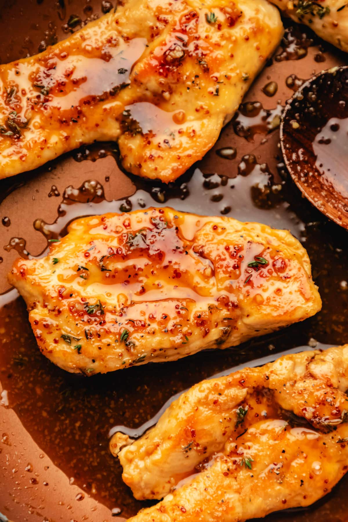 Close up photo of maple mustard chicken breasts in a skillet.