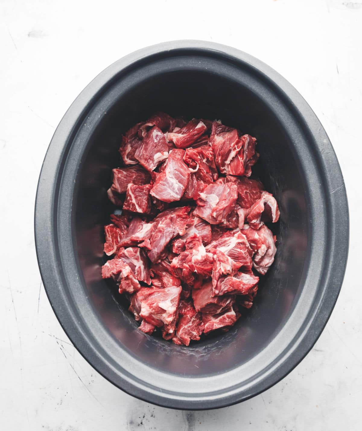 Cubed chuck roast in a slow cooker insert for slow cooker Korean beef.