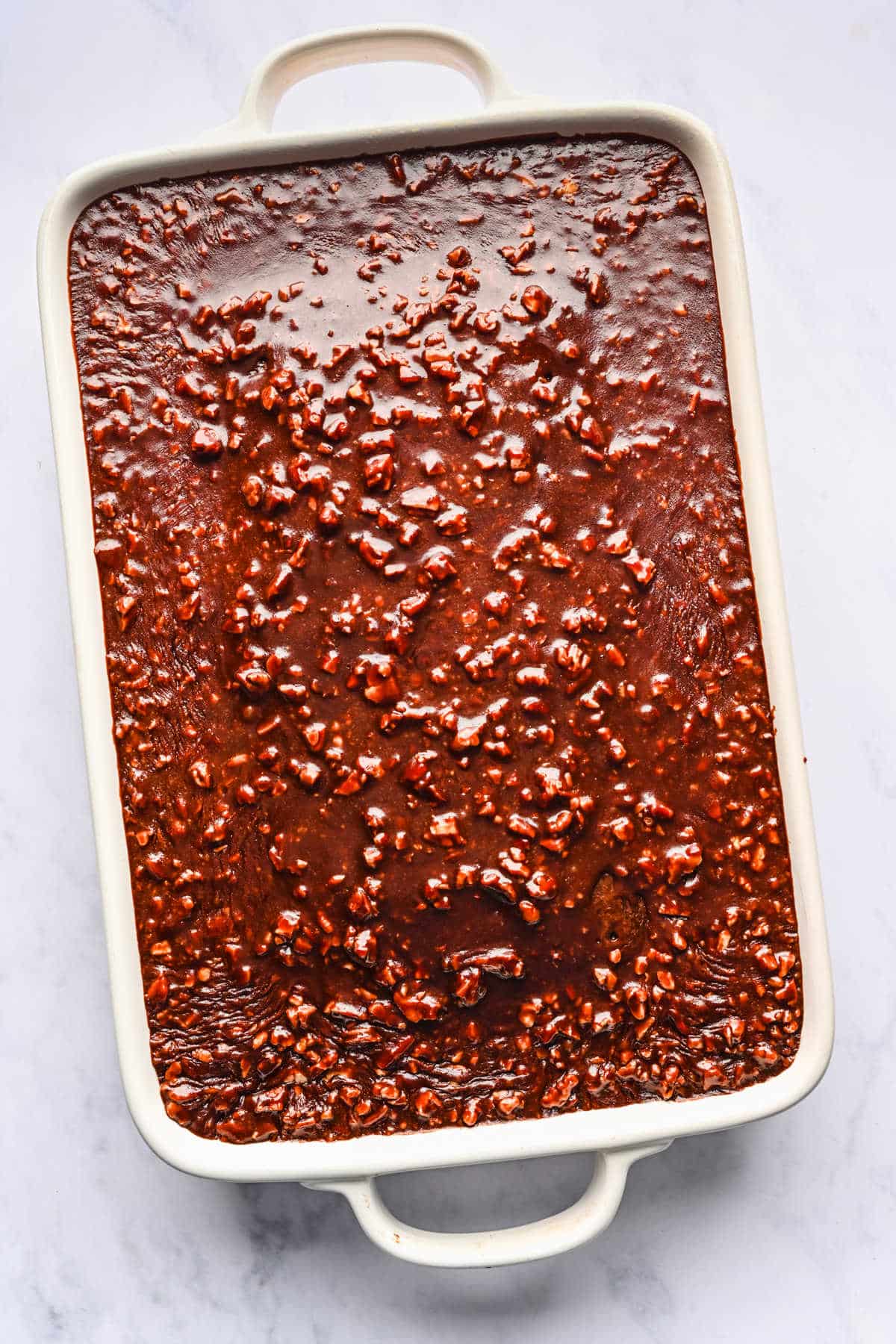 Coca Cola cake icing poured over a hot baked Coca Cola cake.