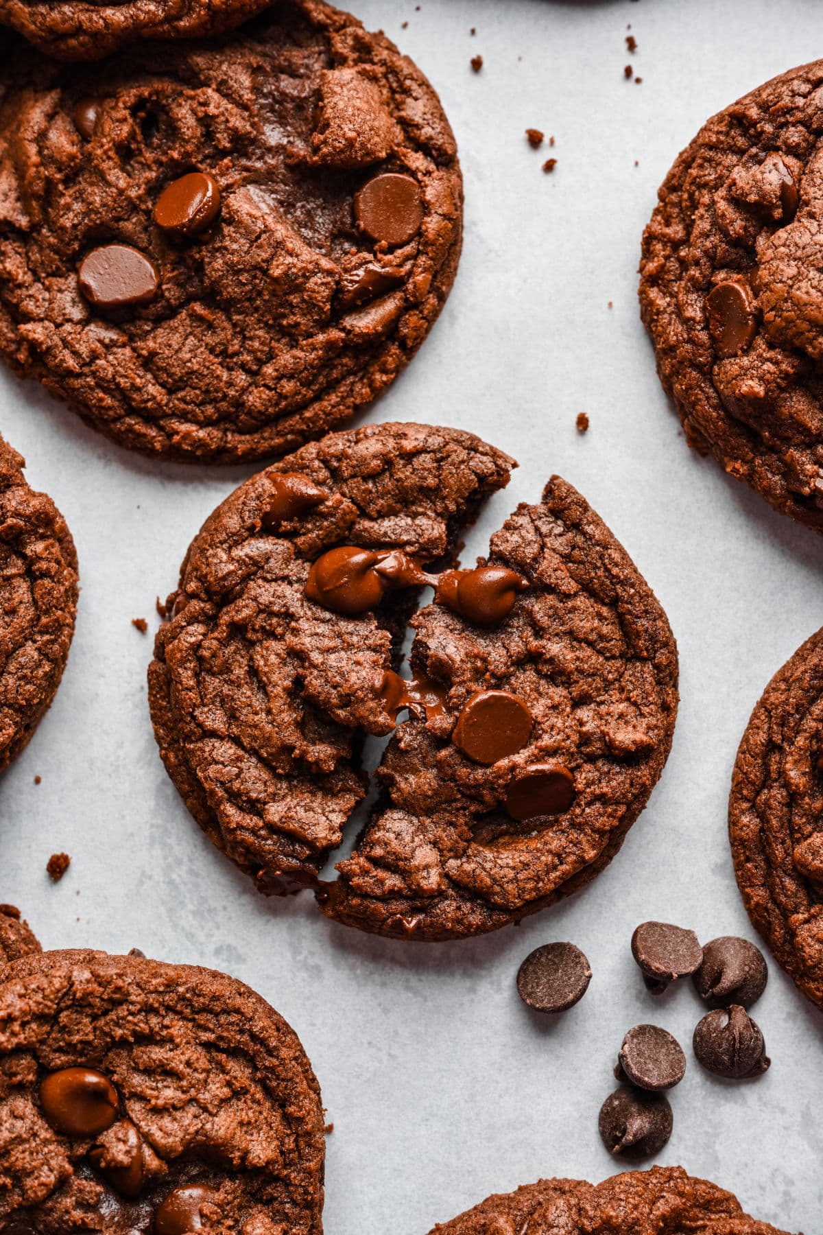 A nutella cookie broken in half on a piece of white parchment paper.