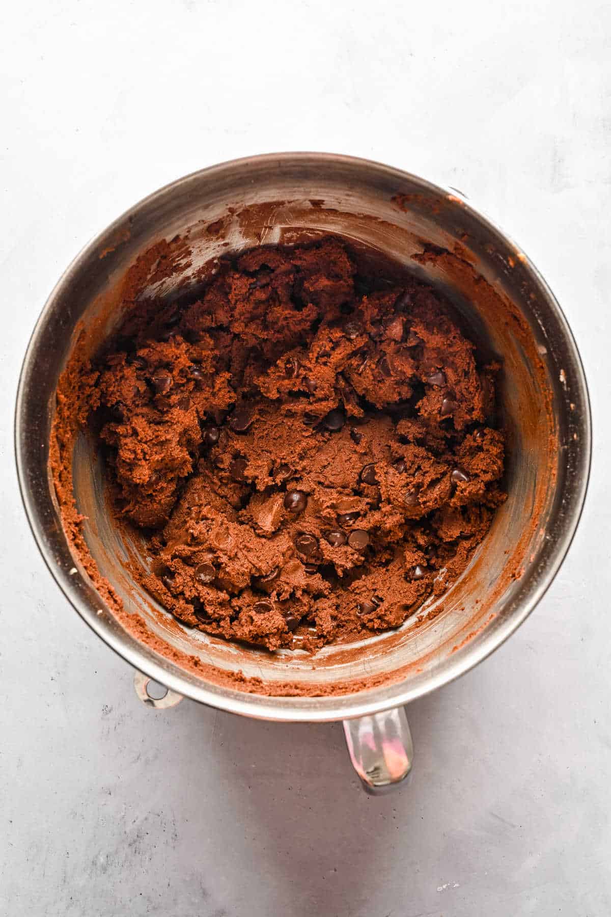 Nutella cookie dough with chocolate chips in it in a silver mixing bowl.