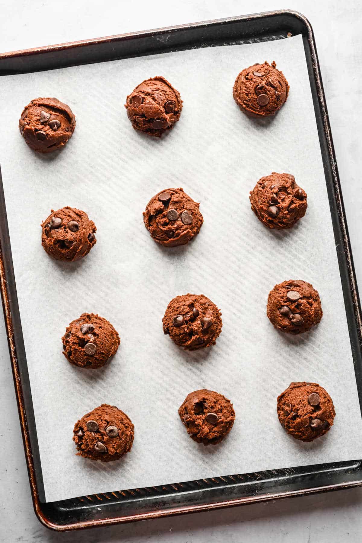 Scoops of Nutella cookie dough on a cookie sheet.