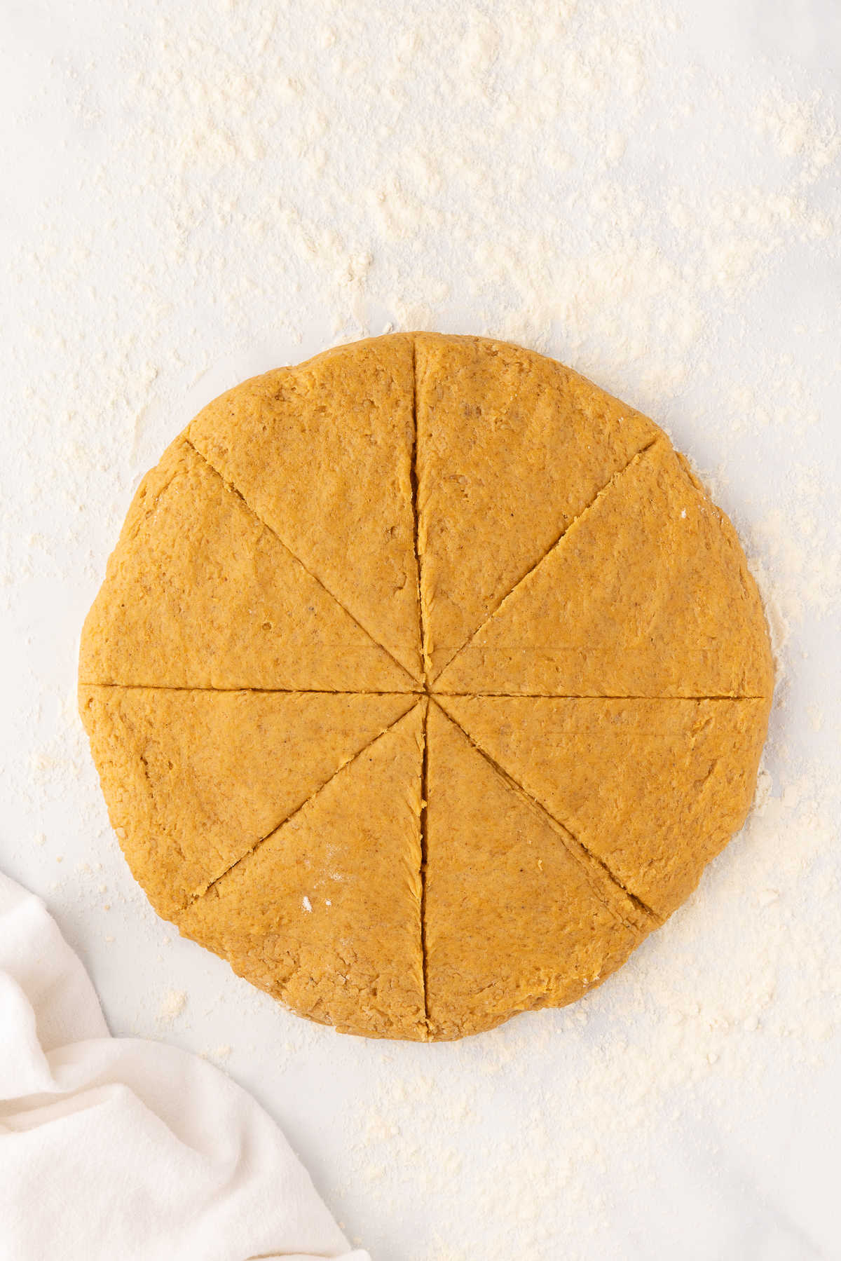 A circle of pumpkin scone dough cut into 8 pieces. 
