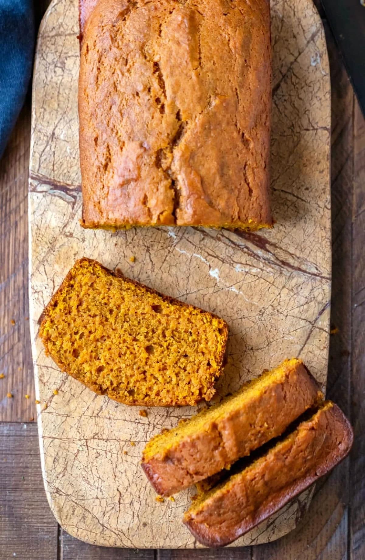 Three slices of pumpkin bread next to the loaf.