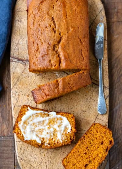 Sliced pumpkin bread on a marble cutting board.