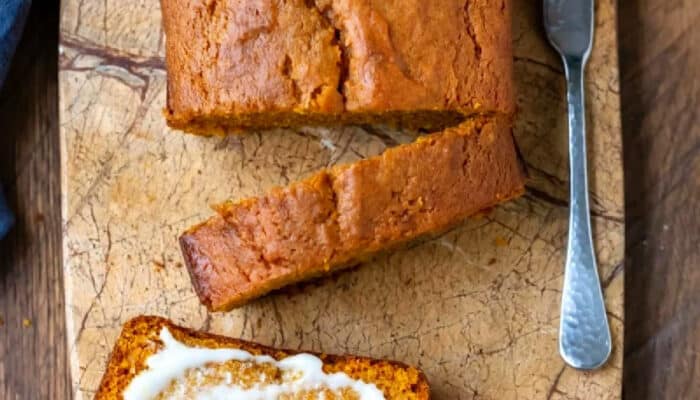 Sliced pumpkin bread on a marble cutting board.