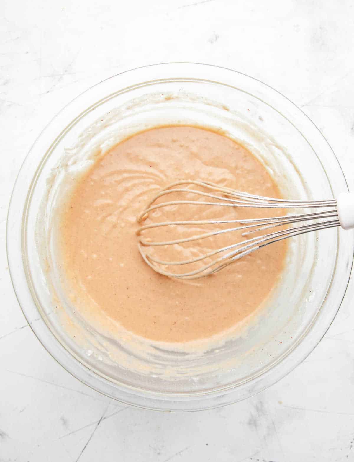 Apple cider donut hole batter in a glass mixing bowl. 