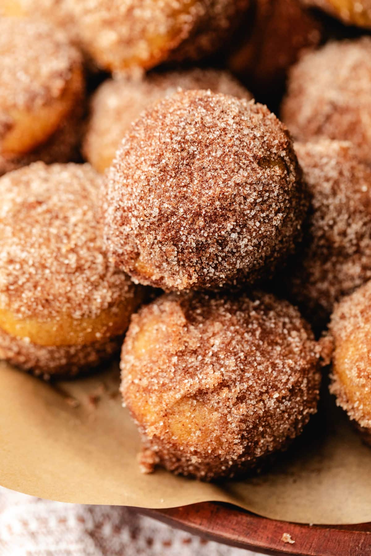 A wooden tray full of stacked apple cider donut holes.