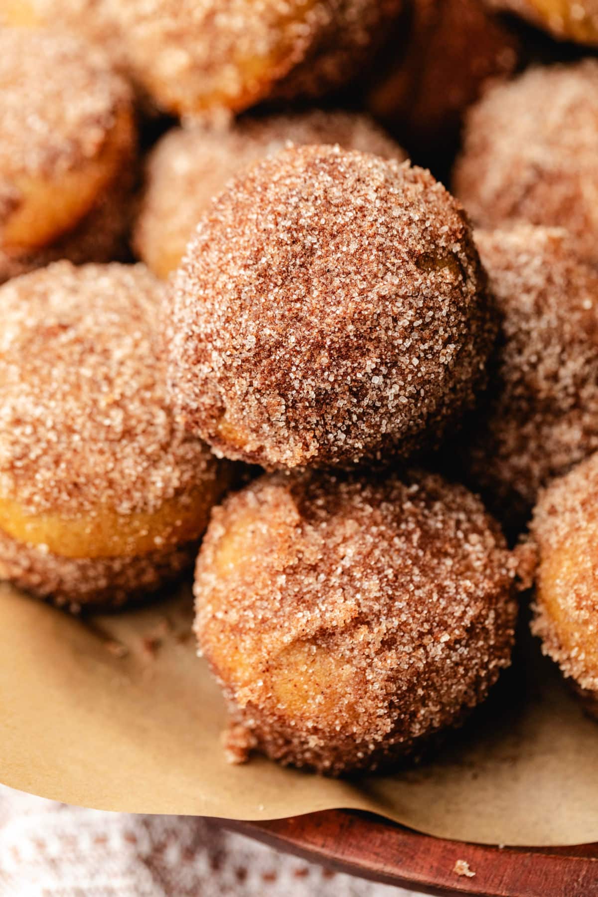 A wooden tray full of stacked apple cider donut holes. 