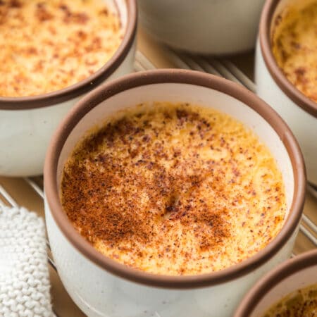 A dish of baked custard between two other custard dishes on a wire cooling rack.