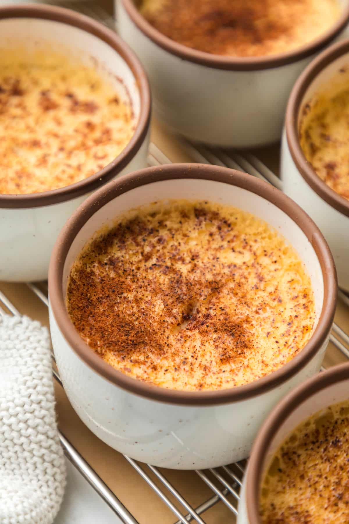 A dish of baked custard between two other custard dishes on a wire cooling rack.