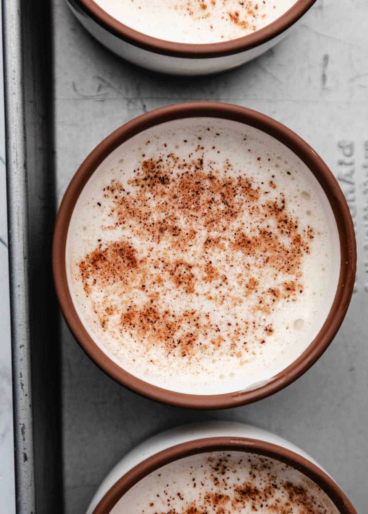 Nutmeg sprinkled onto egg mixture in a ramekin.