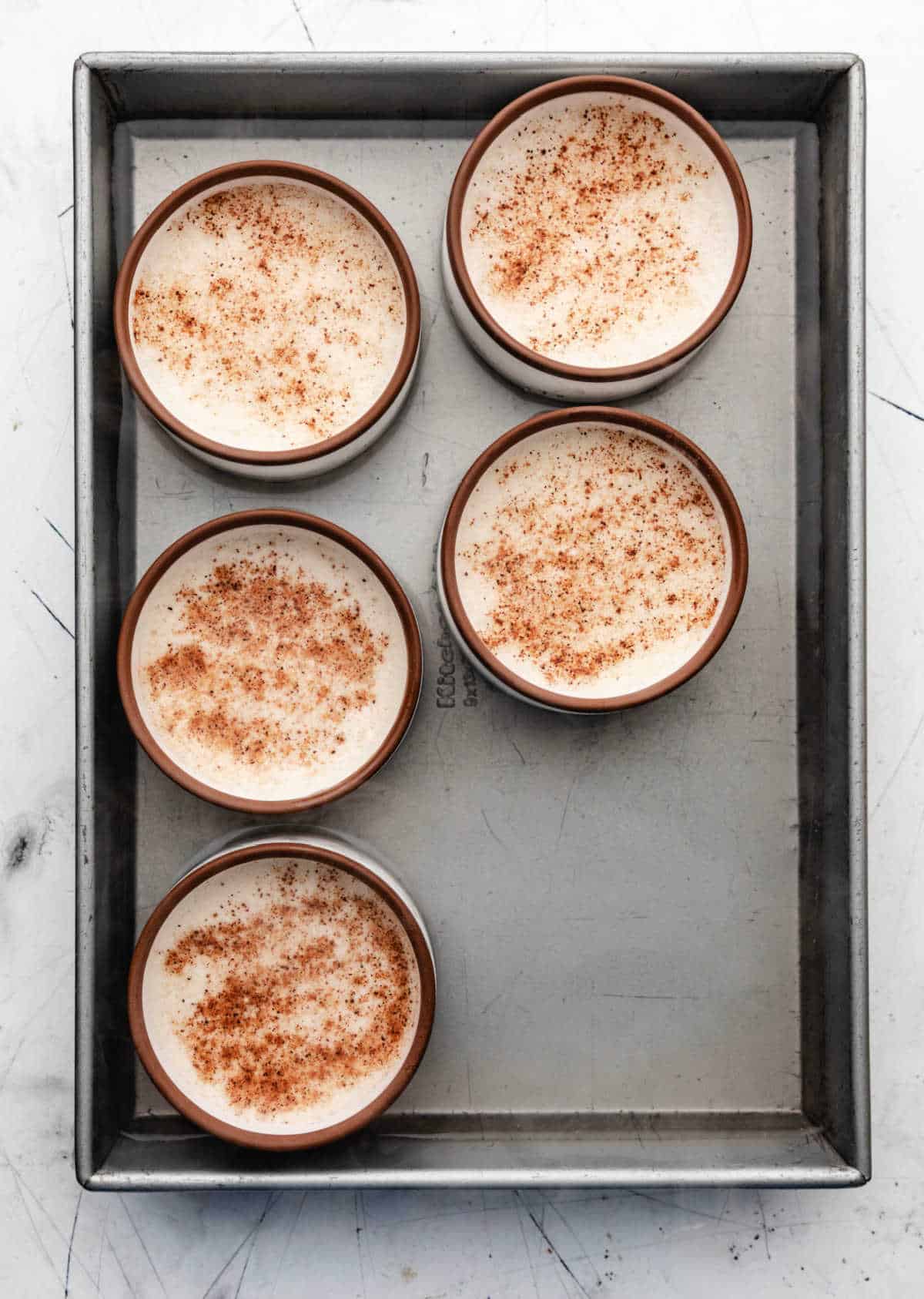 Boiling water in a baking dish full of custard cups.