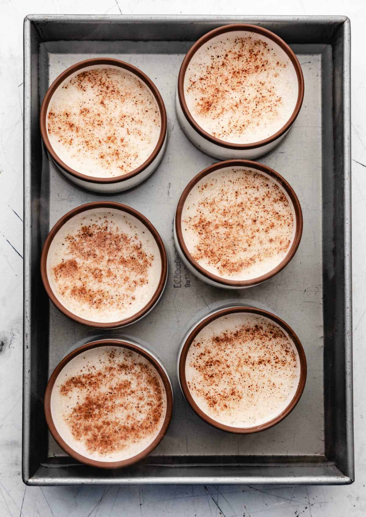 Ramekins in boiling water in a baking pan.