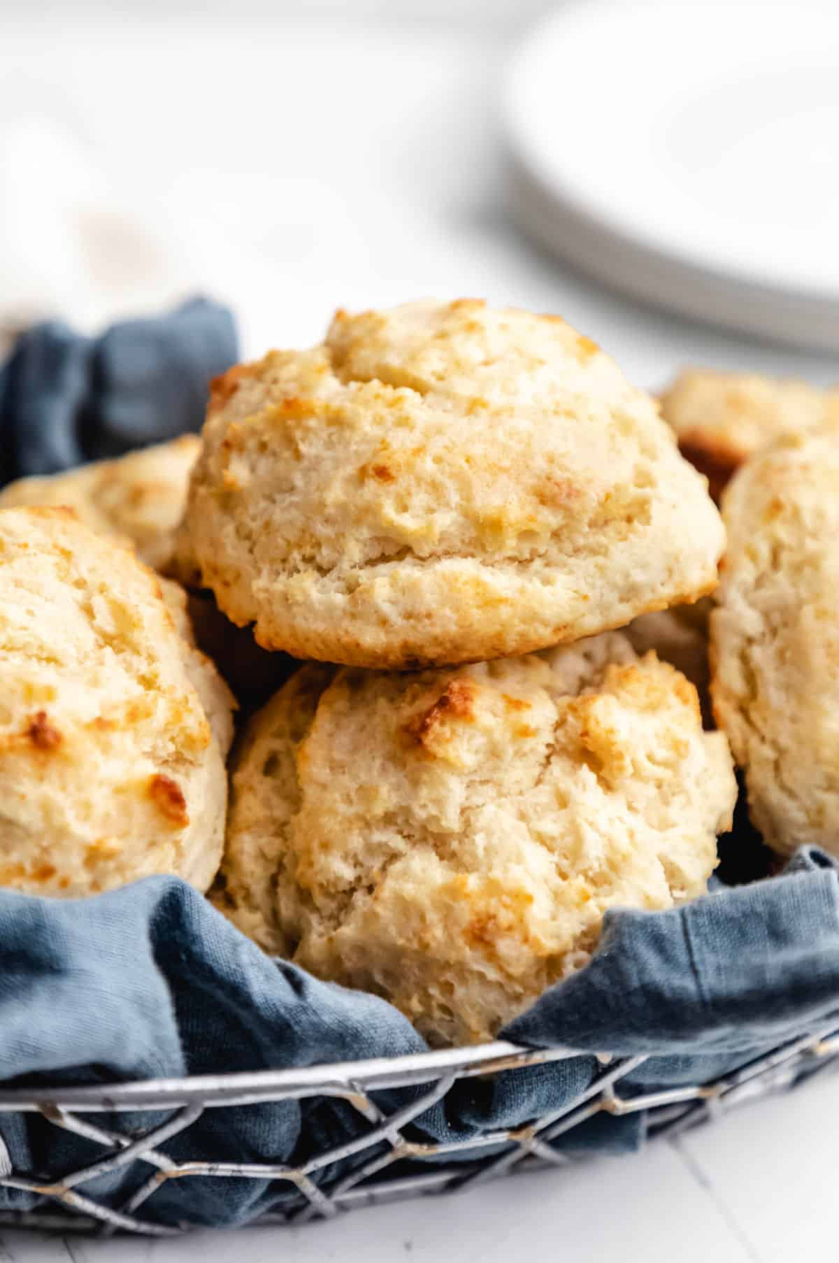 A basket of buttermilk drop biscuits lined with a blue linen.