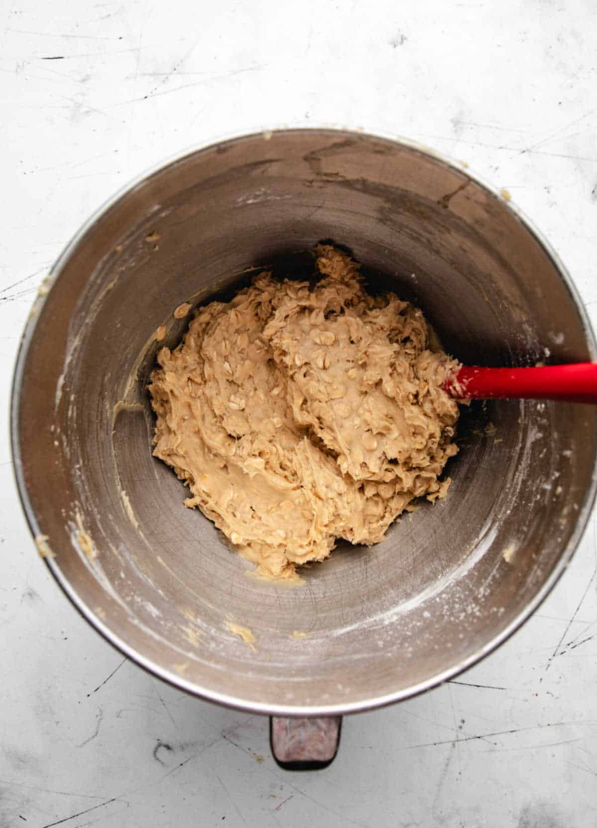 Oatmeal cookie batter in a silver mixing bowl.
