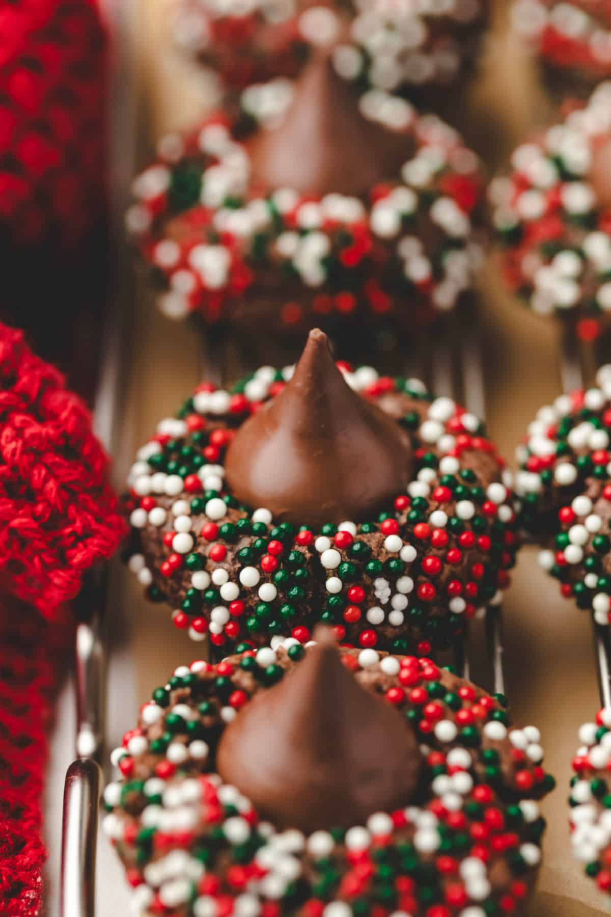 A row of Christmas cookies next to a red knit napkin. 