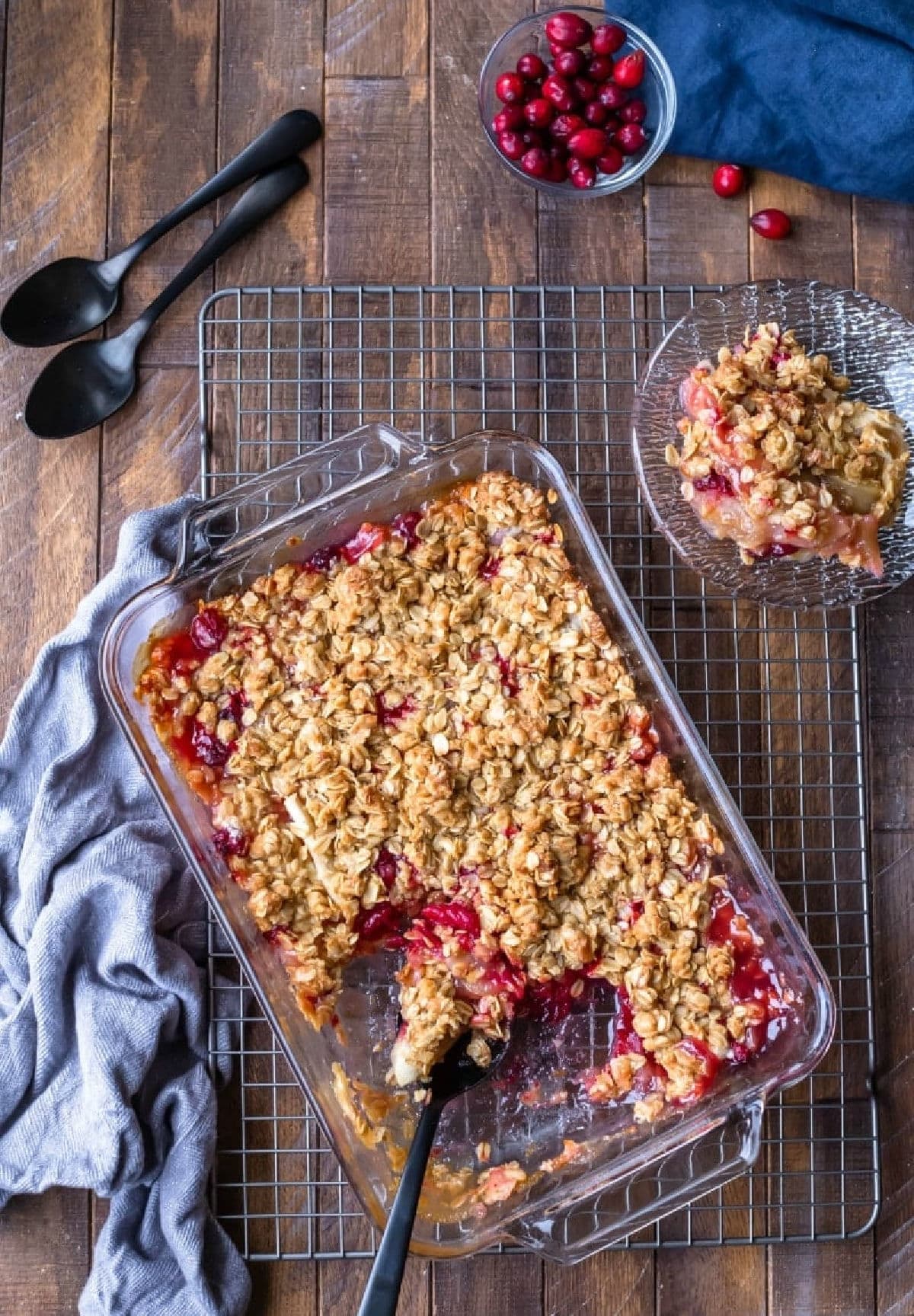 A glass dish of cranberry apple crisp next to a plate of crisp.